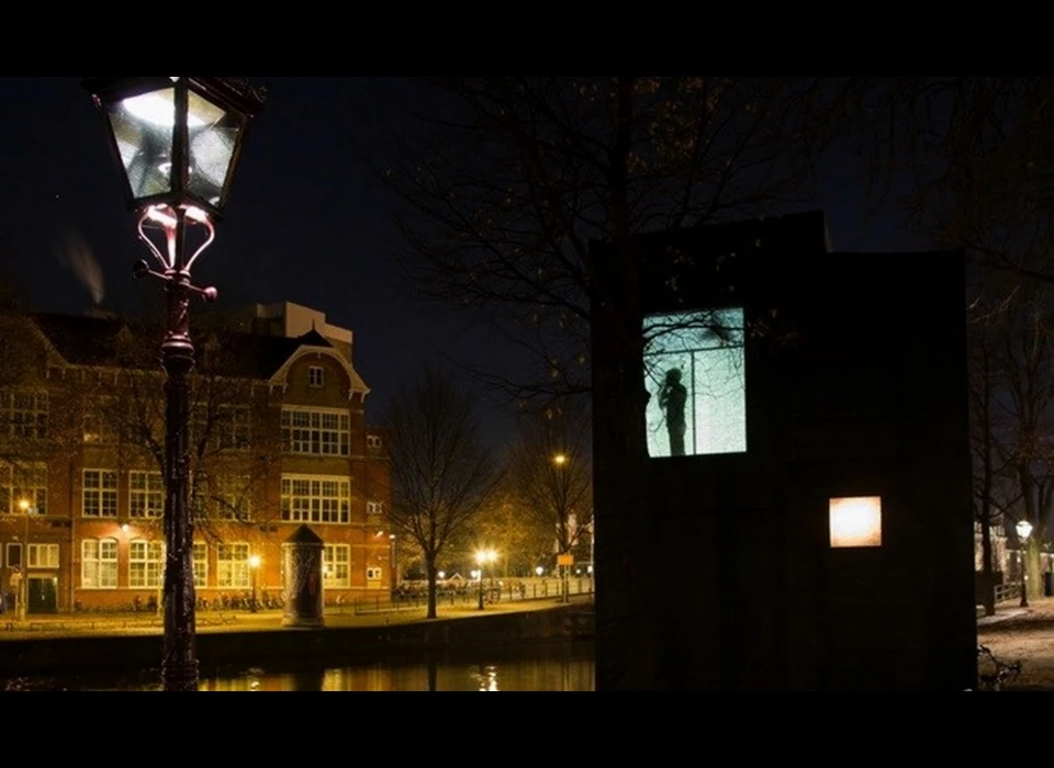 'What's he building in there?' Het silhouet van een persoon beweegt achter een raam. Wat is hij aan het doen? Onze nieuwsgierigheid is onbedwingbaar; 
					  deze installatie van Laurent de Wolf confronteert ons met deze ongeremde fascinatie voor de levens van anderen. Deze installatie komt ’s avonds tot leven. Is de persoon achter het raam een performer of zijn wij 
					  simpelweg voyeurs? De fantasie van de kijker wordt gestimuleerd. Wat iemand doet in zijn eigen huis is niet onze zaak, of wel? We zijn allemaal immers medeverantwoordelijk voor het welzijn van de wereld. Of er 
					  daadwerkelijk iets niet pluis is weet je echter niet. (Laurent de Wolf (NL) is een architect, vormgever en oprichter van Out of the Woods Architecture.) 2016