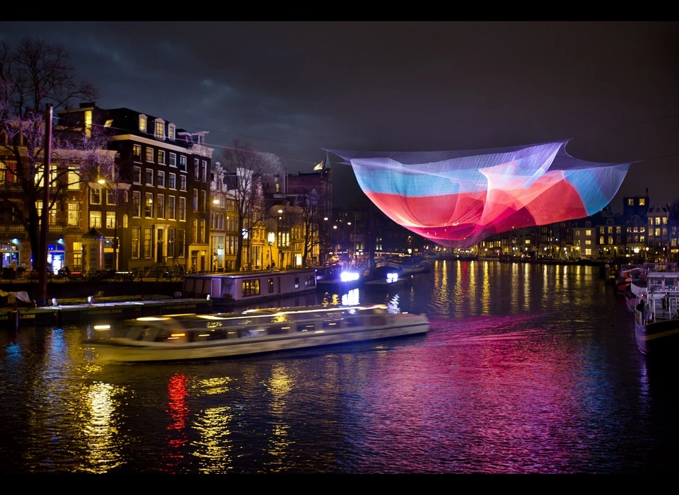 '1.26 Amsterdam' is een verwijzing naar de aardbeving in Chili die in februari 2010 plaatsvond. Deze gebeurtenis zorgde 
					  ervoor dat die dag werd verkort met 1.26 microseconden. (Janet Echelman (US) geeft een nieuwe vorm aan het luchtruim met monumentale en bewegende sculpturen die reageren op omgevingskrachten; 
					  zoals wind, water en zonlicht.) 2012