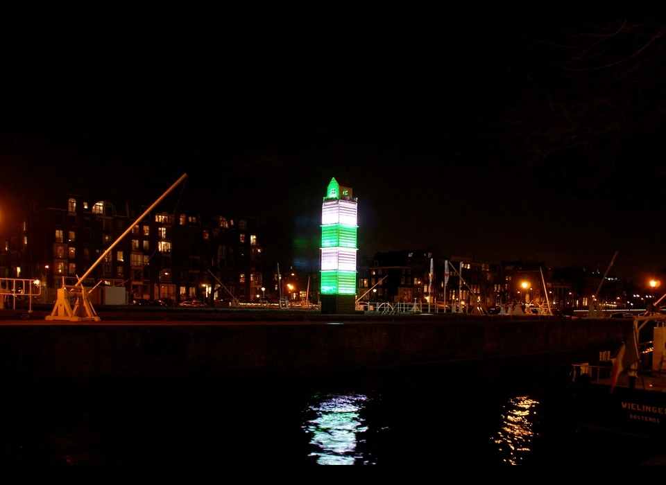 Deze vuurtoren is niet wat het lijkt. Het is een zeecontainer, afkomstig van een schip dat zijn lading verloor. Een wit huisje, omgeven 
					  door een wit houten hekje. Uit het huisje stroomt ’s nachts licht. Het werk is een ode aan Amsterdam, een stad die sterk door de internationale scheepvaart is beïnvloed en gevormd. Tegelijkertijd is 
					  ‘LightHouse’ een eerbetoon aan kunst en verbeeldingskracht. Door te spelen met schaal, verrassende materialen én licht wekken de makers een bepaalde verwachting bij het publiek. (Pitaya (FR) is een 
					  ontwerpstudio, opgericht door David Lesort en Arnaud Giroud. Het duo ontmoette elkaar tijdens hun studie Industrieel Ontwerpen. Ze zijn gespecialiseerd in lichtkunst.) 2014