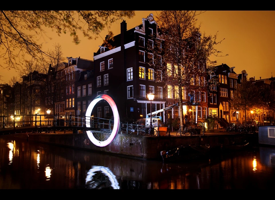 Rob van Houten ontwierp speciaal voor de Melkmeisjesbrug ‘Circle of Life’, een ring van licht rond de brug die de kunstenaar altijd 
					  weer doet voelen alsof hij een stukje boven de stad zweeft. ‘Circle of Life’ is een Möbiusring, het symbool voor oneindigheid. ‘Circle of Life’ gaat hierover: het eindeloze stromen van het water en van mensen 
					  naar de stad. De ring begint melkwit, als een lege stad die moet worden gevuld met leven. Wanneer iemand eronderdoor loopt, golft het licht weerskanten op, om zich met nieuwe kleuren te vermengen. (Rob van 
					  Houten (NL) is architect, ingenieur en ontwerper. Hij studeerde Architectuur en Bouwtechnologie aan de TU Delft.) 2014