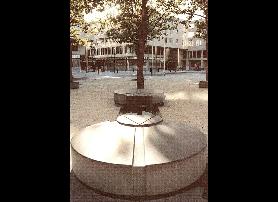 Bijlmerplein 888 De cirkelvormige elementen van kunstenaar Arnold Hamelberg verbinden het gebouw met zijn omgeving 
					  door de as (in blauwe hardsteen) tussen het midden van het plein en de hoofdentree. (1987)