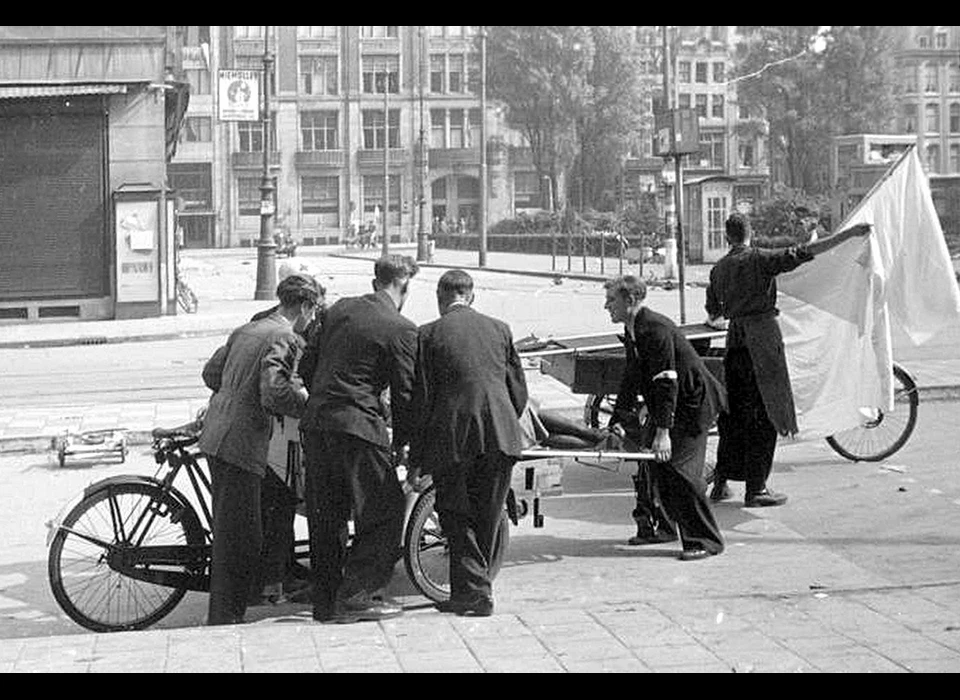 Dam 7 mei 1945 ophalen van een slachtoffer van de schietpartij vanuit De Groote Club