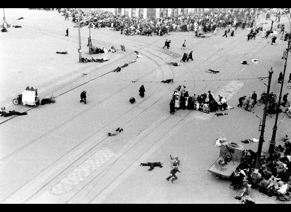 Dam 7 mei 1945 dekking zoeken op het plein voor de schietpartij door Duitse soldaten vanuit De Groote Club op de hoek van Paleisstraat en Kalverstraat