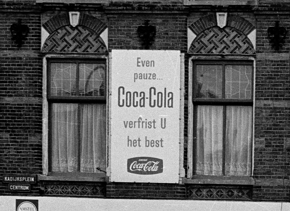 Kadijksplein 11 reclame voor Coca Cola door CocaCola op een apart bord over bestaande gevelreclame (1967)