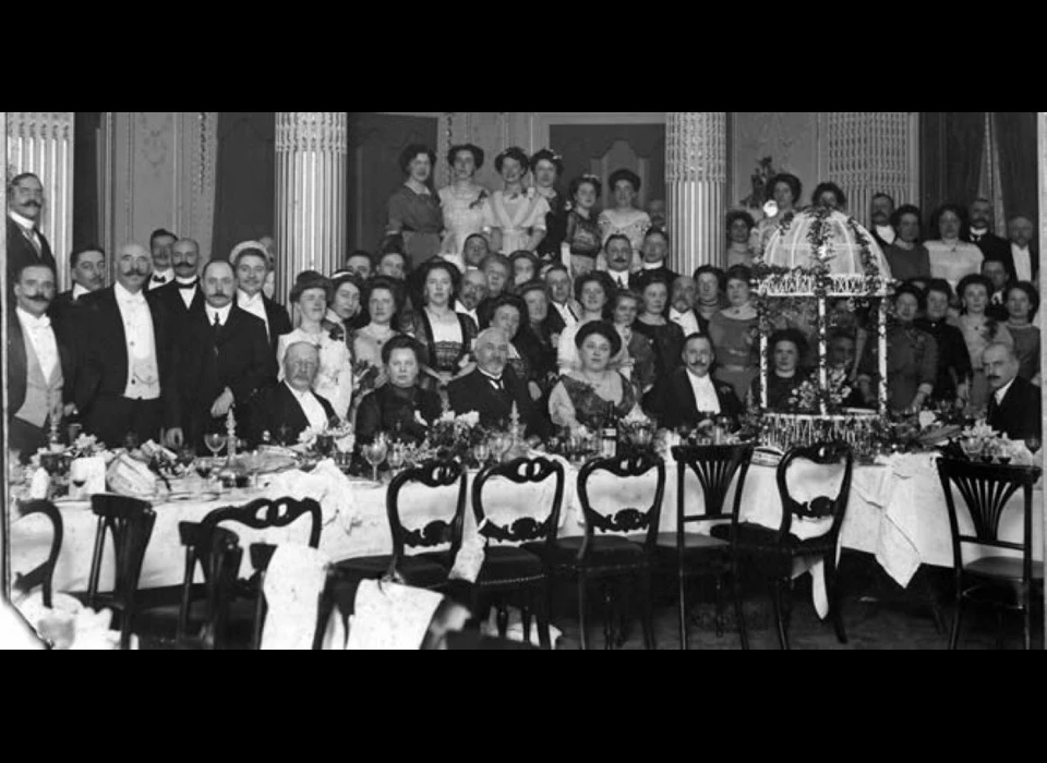 Diner in Huize Couturier aan een feestelijk gedekte tafel (ca.1884). Johannes Jacobus Couturier verzorgde het diner, dat de gemeenteraad aan burgemeester Jonkheer Mr. Dr. A. Röell in 1911 aanbood.
						De officieren van het Noorse schip Frithjof werden in 1912 onthaald, dan zijn er promotiediners, officieren van de schutterij, de Maatschappij van Nijverheid, de Internationale Bakkerij tentoonstelling, 
						de Conférence Europïenne Combinée des Honoraires et des Voitures Directes, de Kamer van Koophandel, Olympische Comités. Het is maar een greep want daartussendoor zijn er diners ten  stadhuize en ten paleize.