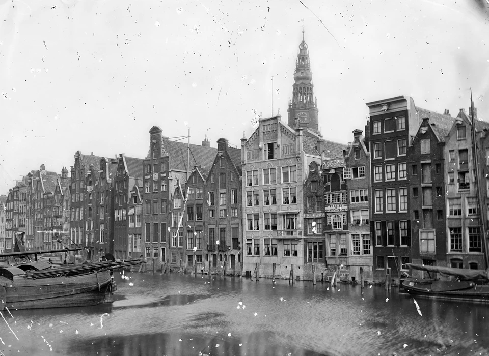 Bible Hotel (onder de toren) gezien over het water van het Damrak (1875)