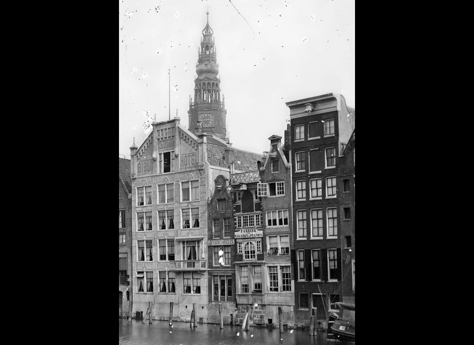 Bible Hotel (onder de toren) gezien over het water van het Damrak (1875)